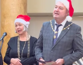 The Lord Mayor and Sheriff of York, wearing Christmas hats and chains of office, singing carols at a Christmas Cheer reception