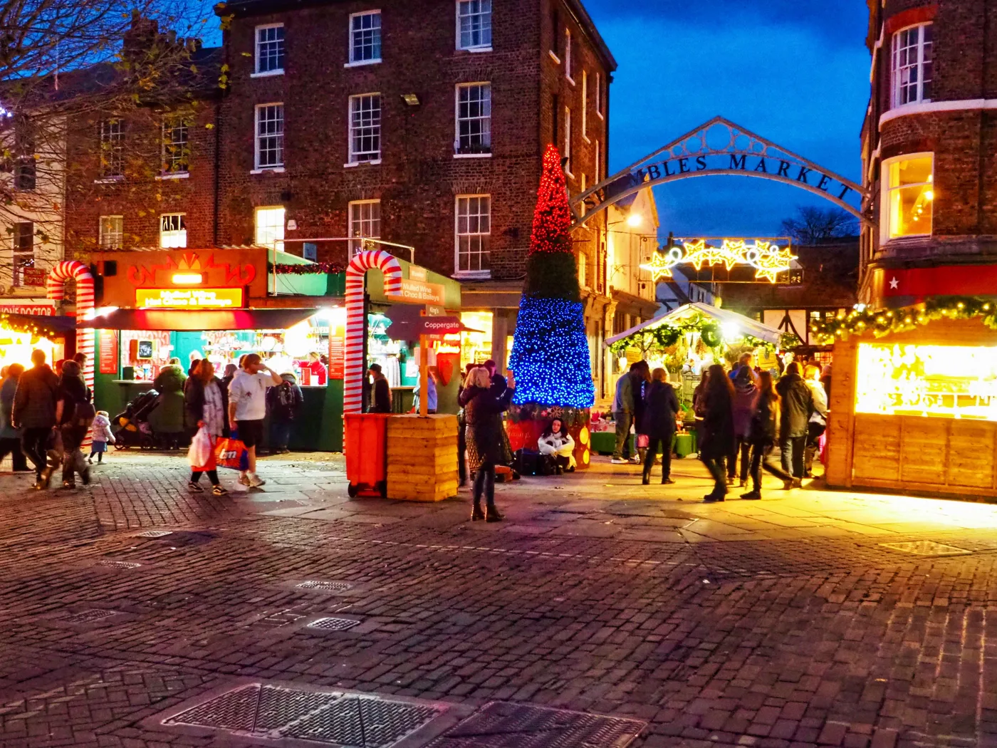 Christmas Market stalls on Parliament Street, by the Shambles Market arch, at dusk