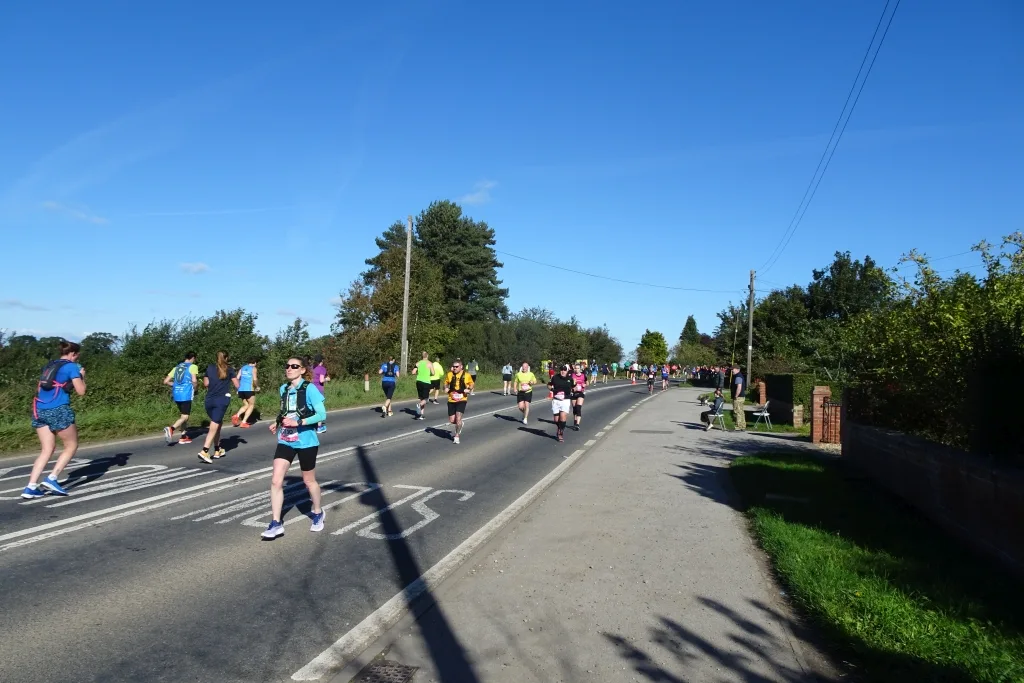 Runners on the closed A166 between Stamford Bridge and Dunnington during the Yorkshire Marathon, under a clear blue sky